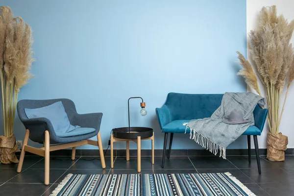 Turkos soffa och stol, klassiskt vardagsrum dekoration, blå vägg, matta på mörkt trägolv, interiör stil Stockbild
