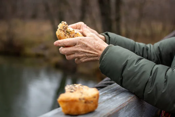 Herbst, Nahaufnahme alter Frauenhände, die Brot von der Brücke bröckeln. — Stockfoto