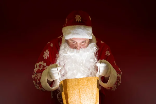 O Pai Natal abre um saco de papel com uma surpresa. luz está vindo do pacote. — Fotografia de Stock