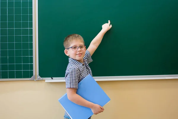 Egy kék inges iskolás fiú mutatóujjával a táblára mutatott.. — Stock Fotó