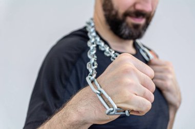 Genç adam yumruğunda demir bir zincir tutuyor..