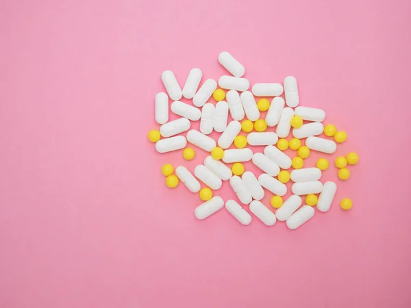Montón de píldoras blancas y amarillas sobre fondo de papel rosa. Surtido de medicamentos farmacéuticos. Concepto de salud y medicina. Tratamiento de virus. Composición colorida y elegante. —  Fotos de Stock