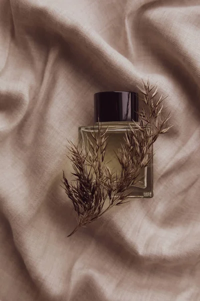 Minimal fashion composition with bottle perfume and beige reeds on linen pastel fabric as background. Toilet water, still life. Flat lay, decoration design. Vertical top view, soft focus. Minimalism — Stock Photo, Image