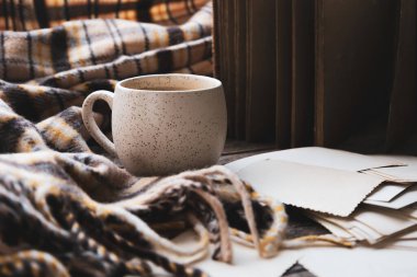 Atmosferik sıcak kahve kupası, rahat kahverengi ekose ve eski aile fotoğrafı. Pazar yalnızlığı rahatlatıcı, sarılma havası. Ataların anıları, aile bağları, çocukluk anıları. Bardağa hafifçe odaklan