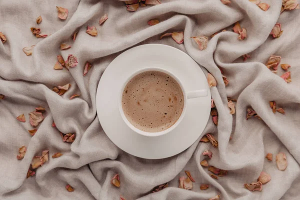 Herbstlicher Morgenkaffee. Trockene Blätter und Blütenblätter, Cappuccino und Leinenstoff als Hintergrund. Sonntagsruhe, Umarmungsstimmung und Stilllebenskonzept. Minimalismus Herbst Komposition mit pastellfarbenen neutralen Farben. — Stockfoto