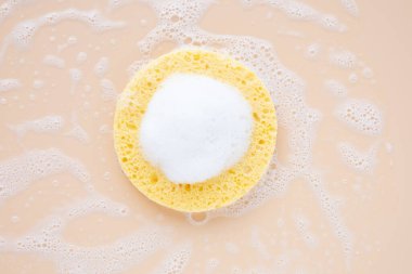 Doğal bej kozmetik süngerle temizleyici köpük ve pastel arka plan. Sabah ya da akşam güzellik rutini. Yüz konsepti için güzellik. Üst görünüm