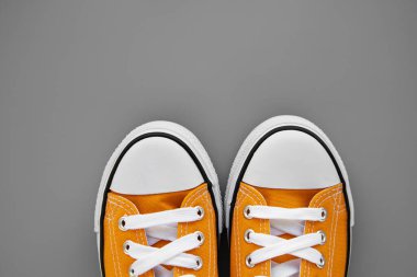 Gri arka planda iki sarı kadın kumaş spor ayakkabısı. 2021 yılının renkleri. Şık genç rahat ayakkabılar, gerçek sıradan ayakkabılar. Minimalist ayakkabı mağazası reklam tarzı. Boşluğu kopyala