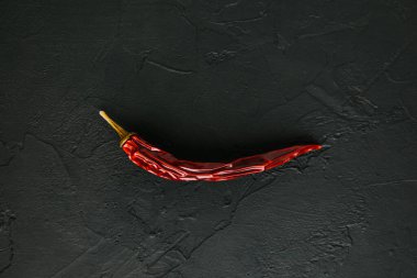 Tayland yemekleri için en popüler baharatlı bitki. Capsicum frutescens 'ın kurutulmuş meyvesi. Siyah taştan arka planda kırmızı kırmızı kırmızı biber. Yemek pişirmek için baharatlar ve baharatlar. Üst Manzara. Yumuşak odak