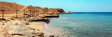 Palm Beach şemsiyeli Sandy ve Rocky Coast. Kızıl Deniz kıyısındaki ıssız tatil köyü plajı. Sharm el Sheikh, Sina, Mısır, Asya yaz sıcağında. Coronavirüs zamanında seyahat edin. Panorama