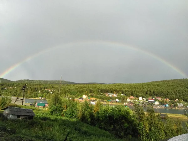 The sun\'s rays lit up the village after the rain and a rainbow appeared in the sky