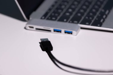 Süper makro fotoğraf çekimi siyah bir kabloya odaklanmış durumda. Kablo, USB-C adaptörü ve dizüstü bilgisayar odaklı değil.