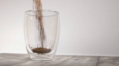 Fotoğraf: beyaz arkaplan önünde boş termo bardak: granüler kahve tozu fincana dökülüyor, yavaş hareket