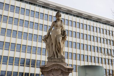 Gökdelenin önündeki antik kumtaşı kadın heykeli, fotoğraf kompozisyonları için ideal.