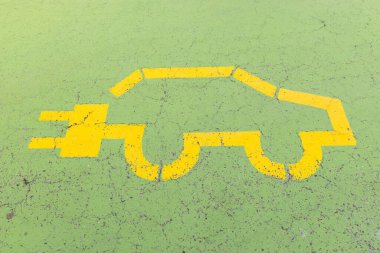 Yeşil beton zemine insanlar olmadan sarı elektrikli araba sembolü çizilmiş.