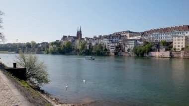 Basel İsviçre, 24 Nisan. 2021: Ren manzarası, nehirde yüzen mavi eski yolcu sürat teknesi, ön planda iki kuğu, arka planda belediye binası olan eski bir havza, gün boyunca güneş ışığı.