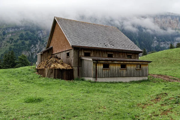 Evin önünde büyük gübre yığını olan yeşil bir çayırda İsviçre dağı ahırı, gübre çiftçilik için iyidir, bu ev özellikle fotoğraf kompozisyonları için iyidir.