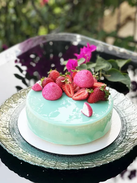 Turkuaz bir tabakta pasta var. yanında bir filiz Bougainvillea.