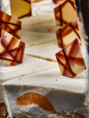 Katmanlı peynirli kek karamelli tatlı kareleri ve beyaz mermer yüzeyde çizgili çikolatalı garnitür. Tatlı Arkaplan