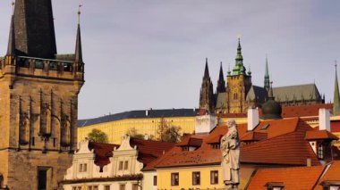 Prag Charles Köprüsü 'nün Gotik kuleleri ve Prag Kalesi manzaralı ve altın saat boyunca doğal ışıklandırmalı heykel görüntülerinin yavaş çekimde 4K B-roll görüntüleri
