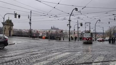 Prag, Çek Cumhuriyeti 11 Şubat 2026: Kırmızı ve beyaz tramvaylar şehir merkezindeki tarihi binaların yakınlarındaki kaldırım taşı caddelerde seyahat ediyor, 4K sinematik B-roll görüntüleri. Düzenleyici kullanımı