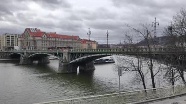 Prag, Çek Cumhuriyeti 13 Şubat 2026: Tarihi köprü bulutlu kış gününde Vltava Nehri 'ni tramvay geçişi ve tur teknesiyle kaplıyor. Sadece editör kullanımı.