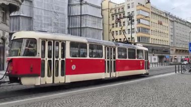 Prag, Çek Cumhuriyeti 19 Şubat 2026: Kırmızı ve beyaz tramvay yayalar, inşaat iskeleleri ve karışık mimari araçlarla şehir caddesinde duruyor. Sadece editör kullanımı.