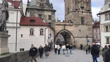 Prag, Çek Cumhuriyeti 24 Şubat 2026: Parlak bir kış günü öğleden sonra Charles Köprüsü 'nü geçen bir turist topluluğu, kaldırım kaldırımının üzerindeki süslü kaidelerin üzerinde duran büyük Barok taş heykellerinin her iki tarafında da yer aldı..