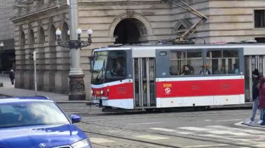 Prag, Çek Cumhuriyeti 24 Şubat 2026: Etkileyici bir kış sabahı, gösterişli neoklasik taş cephesi olan Vltava seti üzerindeki görkemli Ulusal Tiyatrosu 'nun önünden uzun, kırmızı ve beyaz bir tramvay geçiyor