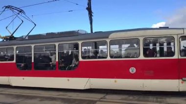 Prag, Çek Cumhuriyeti 24 Şubat 2026: Cesur, çok renkli, beyaz ve kırmızı bir tramvayla çarpıcı bir modern tramvay, Vltava nehir kenarı boyunca kameraya doğrudan yaklaşıyor