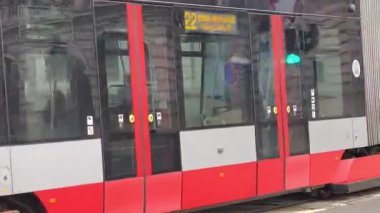 Prag, Çek Cumhuriyeti 24 Şubat 2026: Cesur, çok renkli, beyaz ve kırmızı bir tramvayla çarpıcı bir modern tramvay, Vltava nehir kenarı boyunca kameraya doğrudan yaklaşıyor