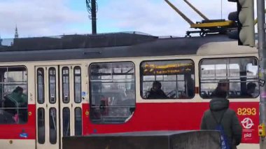 Prag, Çek Cumhuriyeti 24 Şubat 2026: Cesur, çok renkli, beyaz ve kırmızı bir tramvayla çarpıcı bir modern tramvay, Vltava nehir kenarı boyunca kameraya doğrudan yaklaşıyor