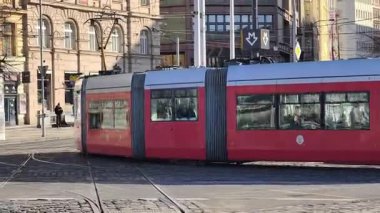 Prag, Çek Cumhuriyeti 24 Şubat 2026: Cesur, çok renkli, beyaz ve kırmızı bir tramvayla çarpıcı bir modern tramvay, Vltava nehir kenarı boyunca kameraya doğrudan yaklaşıyor