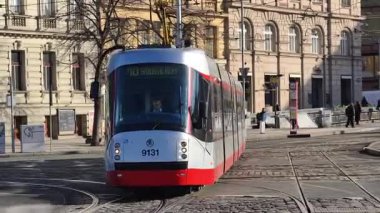 Prag, Çek Cumhuriyeti 24 Şubat 2026: Cesur, çok renkli, beyaz ve kırmızı bir tramvayla çarpıcı bir modern tramvay, Vltava nehir kenarı boyunca kameraya doğrudan yaklaşıyor