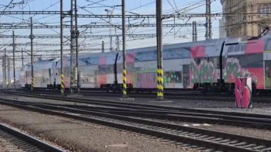 Prag Ana Tren İstasyonu 'ndaki platformda, Orta Avrupa' nın en yoğun ulaşım merkezlerinden birinin günlük atmosferini gösteriyor. Sahne, tarihi terminal, aktif demiryolu operasyonlarının karakteristik mimarisini yakalıyor.
