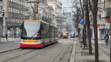 Prag, Çek Cumhuriyeti 27 Şubat 2026: Modern alçak tabanlı tramvay Old Town Meydanı yakınlarındaki 4K yavaş çekimde tarihi mimarinin yanından süzülerek geçti. Bu 4K görüntülerinde modern eklemli bir Prag tramvayı sergileniyor