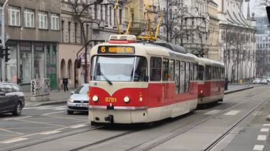 Prag, Çek Cumhuriyeti 27 Şubat 2026: Klasik kırmızı tramvay 4K yavaş çekimde şehir kavşağında kameraya yaklaşırken çekildi. Bu 4K stok görüntüsü herhangi bir Prag makalesi için tam olarak ihtiyacın olan şey.