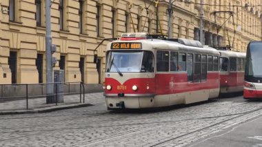 Prag, Çek Cumhuriyeti 27 Şubat 2026: Klasik kırmızı tramvay 4K yavaş çekimde şehir kavşağında kameraya yaklaşırken çekildi. Bu 4K stok görüntüsü herhangi bir Prag makalesi için tam olarak ihtiyacın olan şey.