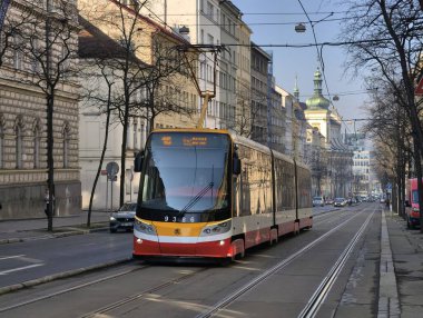 Prag, Çek Cumhuriyeti 6 Mart 2026: Prag 'da merkez bir cadde boyunca, yayalar tarihi Avrupa binaları arasındaki kaldırımlar boyunca yürürken yolcularla birlikte seyahat eden tramvay. Toplu taşımacılık