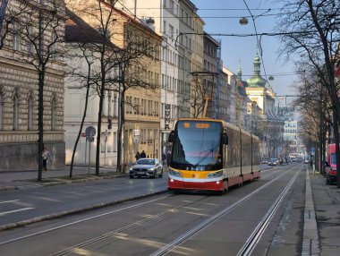 Prag, Çek Cumhuriyeti 6 Mart 2026: Prag 'da merkez bir cadde boyunca, yayalar tarihi Avrupa binaları arasındaki kaldırımlar boyunca yürürken yolcularla birlikte seyahat eden tramvay. Toplu taşımacılık