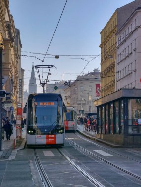 Prag, Çek Cumhuriyeti 6 Mart 2026: Prag 'da merkez bir cadde boyunca, yayalar tarihi Avrupa binaları arasındaki kaldırımlar boyunca yürürken yolcularla birlikte seyahat eden tramvay. Toplu taşımacılık