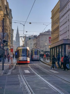 Prag, Çek Cumhuriyeti 6 Mart 2026: Prag 'da merkez bir cadde boyunca, yayalar tarihi Avrupa binaları arasındaki kaldırımlar boyunca yürürken yolcularla birlikte seyahat eden tramvay. Toplu taşımacılık