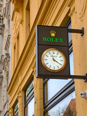 Prag, Çek Cumhuriyeti, 10 Mart 2026 tarihsel şehir merkezi Prag 'ın ön cephesine Crown logo ve sokak saati asılmış lüks Rolex saat mağazası tabelası uluslararası lüks mağaza perakendecisinin vitrininde mimarinin yansıması.