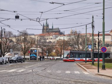 Prag, Çek Cumhuriyeti, 11 Mart 2026, Vltava nehri yakınlarındaki tarihi merkezde günlük yaşam ve ulaşım altyapısı. Yaya geçitlerinden geçen tramvaylar, yolcular ve yayaların yer aldığı şehrin gazetecilik manzarası.