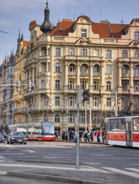 Prag, Çek Cumhuriyeti, 11 Mart 2026, Vltava nehri yakınlarındaki tarihi merkezde günlük yaşam ve ulaşım altyapısı. Yaya geçitlerinden geçen tramvaylar, yolcular ve yayaların yer aldığı şehrin gazetecilik manzarası.