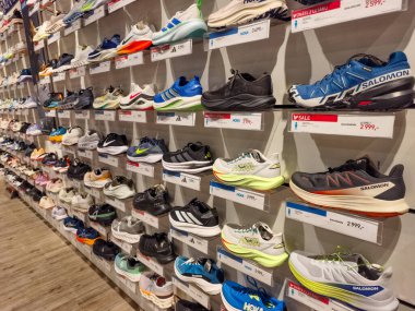 Prag, Çek Cumhuriyeti - 20 Mart 2026: Raflarda uluslararası spor markalarının en ünlü ve modaya uygun spor ayakkabıları koleksiyonunun sergilendiği geniş bir ayakkabı mağaza duvarı manzarası. Modern perakendecilerin gazetecilik bakış açısı