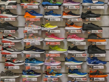 Prague, Czech Republic - March 20, 2026: A wide interior view of a shoe store wall displaying a vast collection of the most famous and fashionable sneakers from international sports brands on shelves. A journalistic perspective of the modern retail