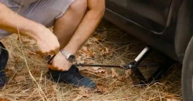 Lastik değiştirmek için arabasını kaldıran bir adam. Yeni tekerlek değiştirme işlemi sırasında Jack 'in aracını kaldırdık..