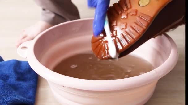 Dámské ruce v gumových rukavicích s kartáčem myje špinavé boty v umyvadle vody — Stock video