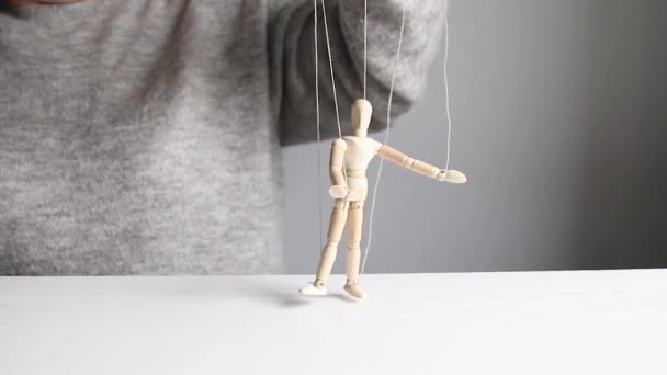 木偶。女人的手可以用灰色背景的线控制一个木制男人的木娃娃 — 图库视频影像