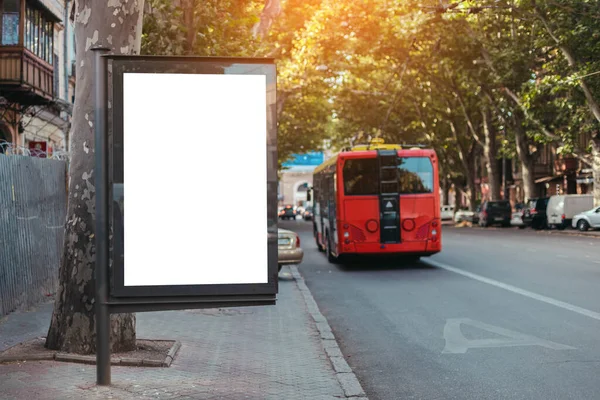 Blank space billboard mock up for advertisement, banner near street road. Red bus travels on dedicated line in the city